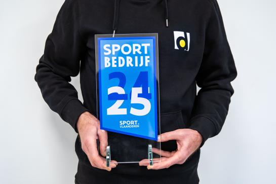 Iemand van de sportdienst houdt de trofee 'Sportbedrijf' vast 